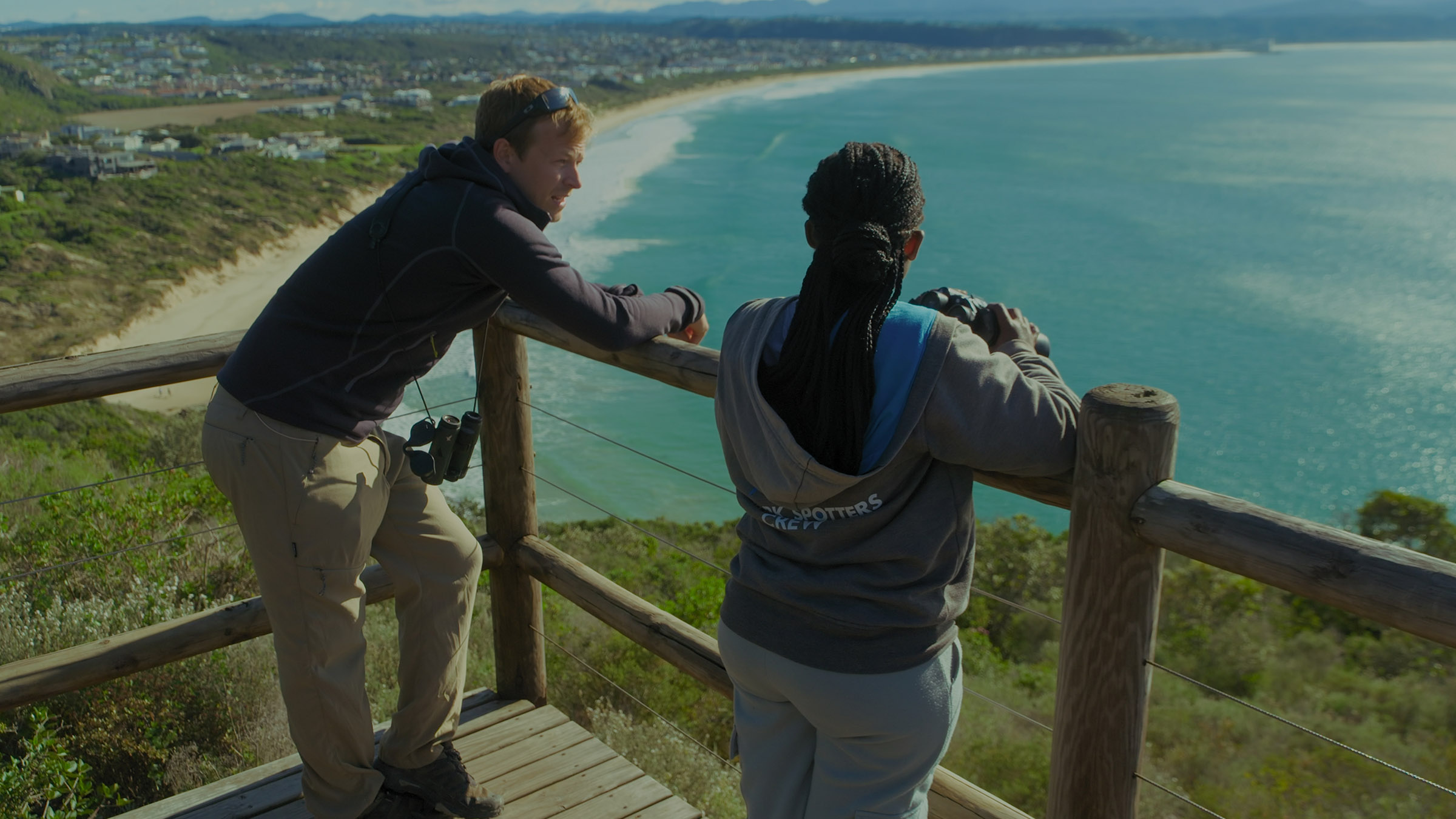Host, Bertie Gregory, looking out over the bay with shark spotter, Kwezi Namntu. Image from... [Photo of the day - July 2025]