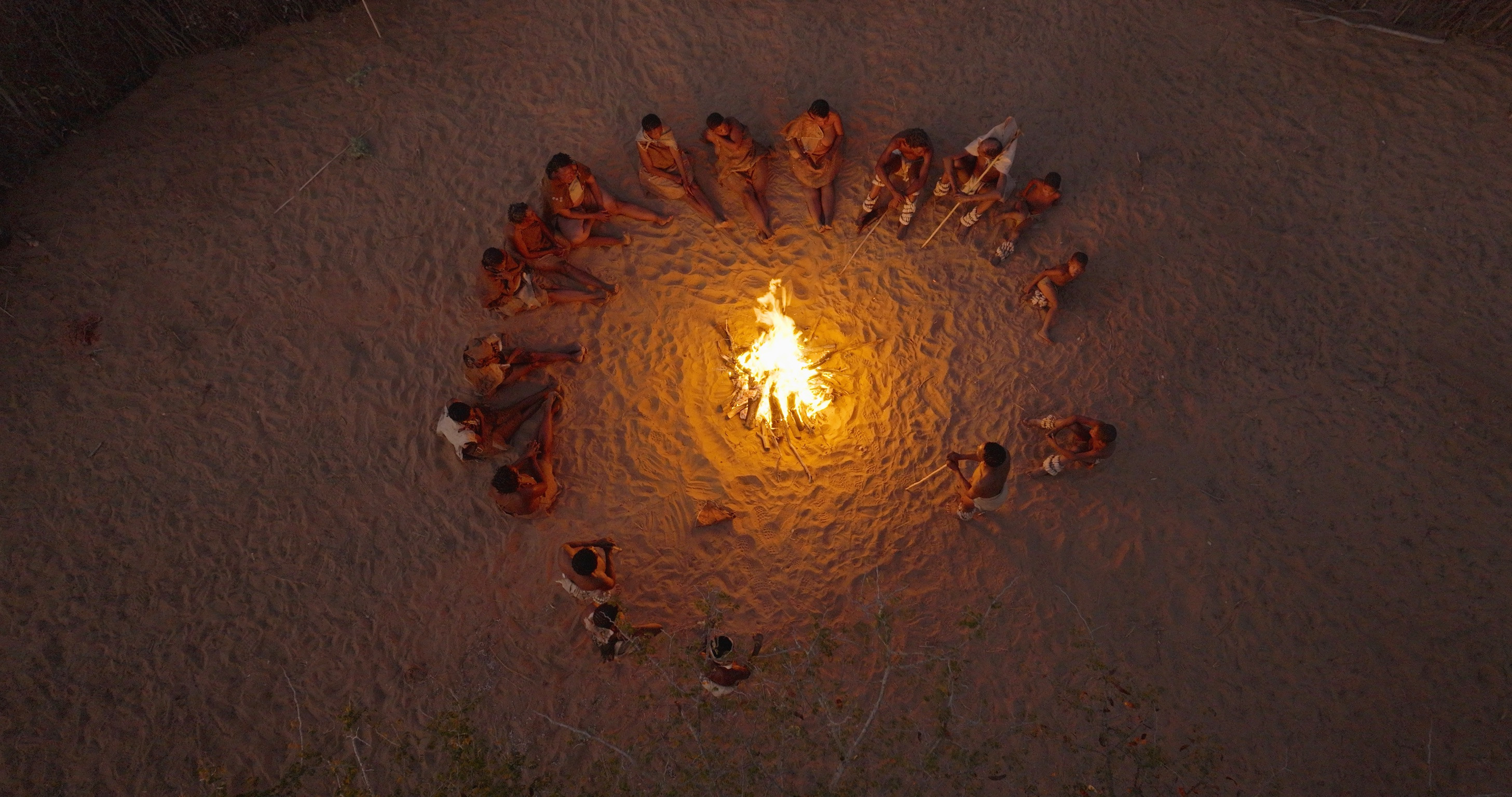 Will and The San sit around a camp fire in Botswana. [Photo of the day - January 2026]